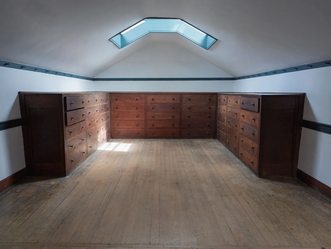 Aménagement sous rampant avec tiroirs bas, bibliothèque en escalier et bureau encastré en bois clair
